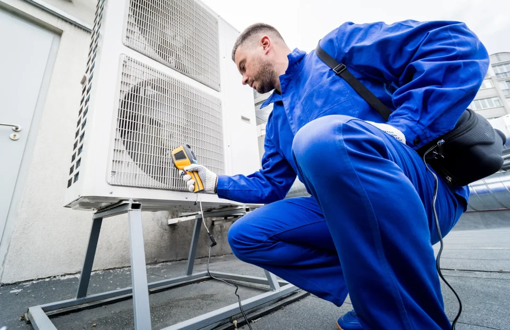 Man in blue coveralls checking on HVAC system